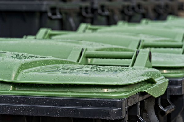 Saubere, grüne Mülltonnendeckel mit Wassertropfen in Reihung